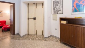 Un couloir avec une porte à deux battants, un meuble en bois et une chaise rouge.