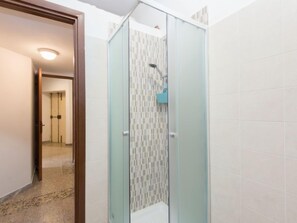 A glass-enclosed shower with a tiled wall and a door leading to a hallway. - Aurelia by Interhome (Rome)