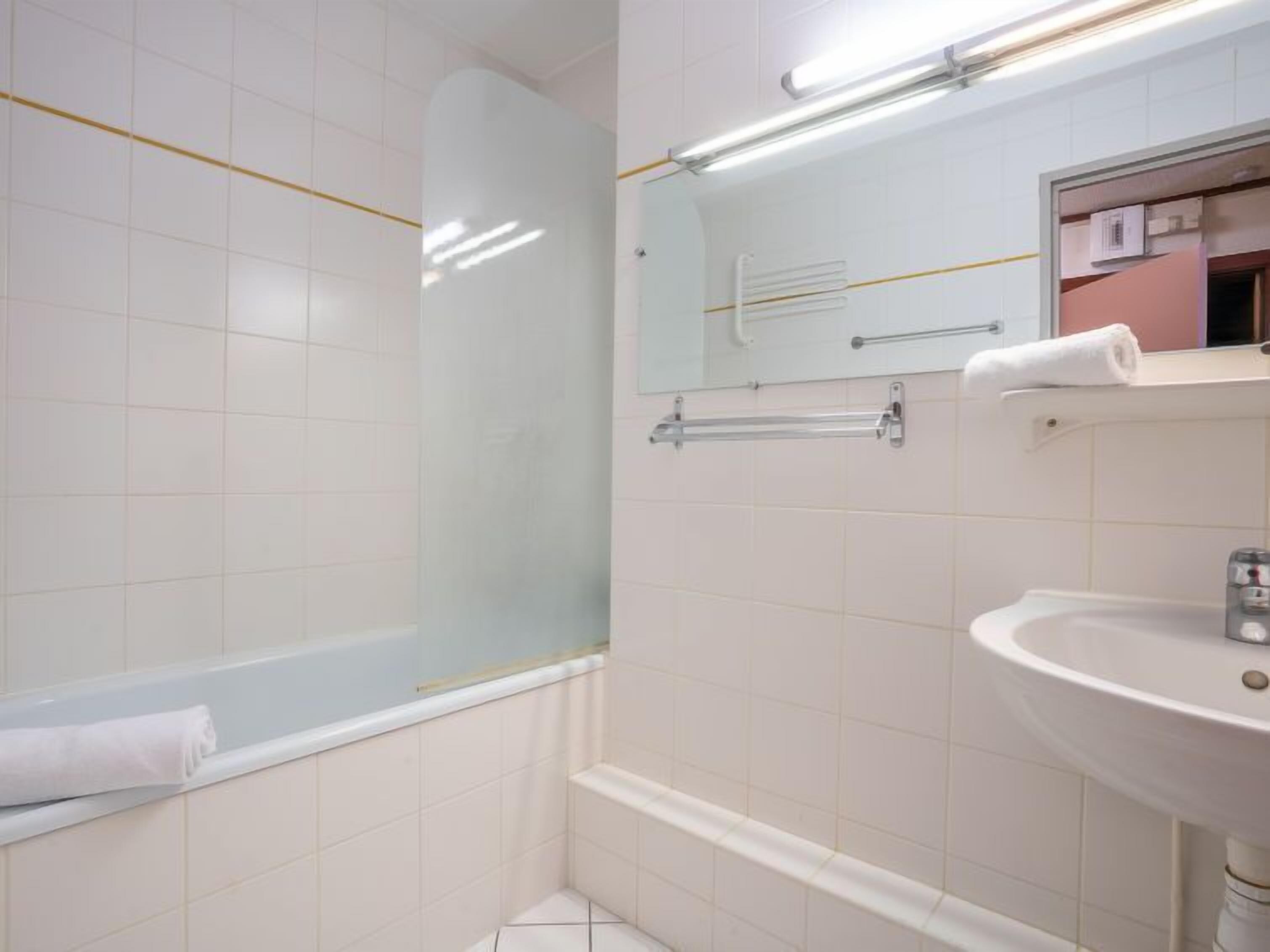 A modern bathroom with a glass shower enclosure, a white sink, and a mirror above the sink.