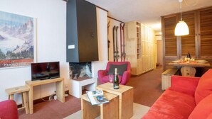 A cozy living room with a fireplace, a television, a red sofa, and a wooden coffee table.