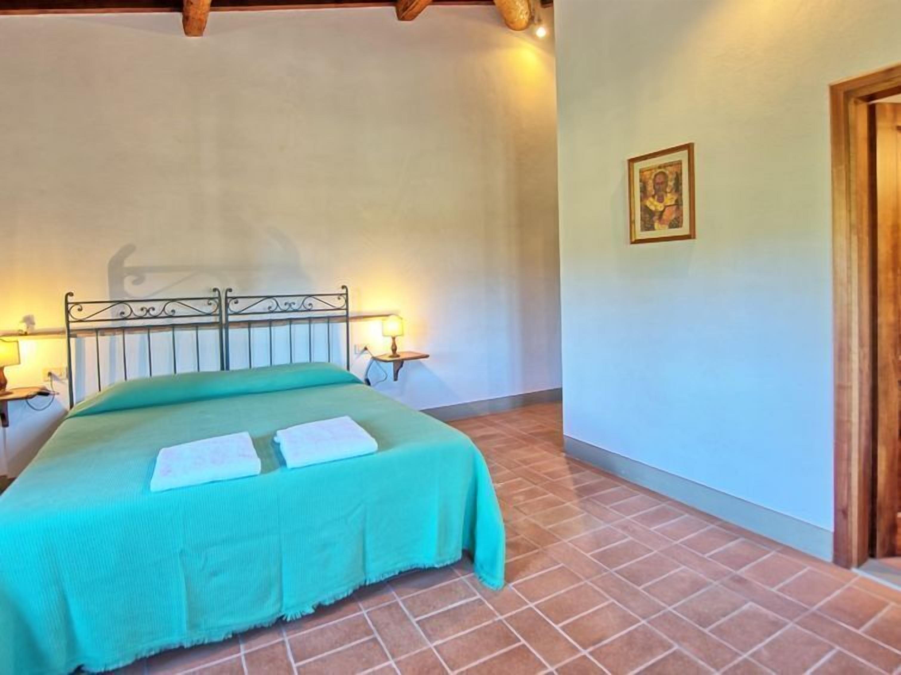 Una camera da letto con un letto, due abat-jour, un quadro incorniciato appeso al muro e una porta in legno.
