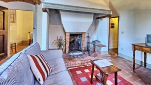 A cozy living room with a fireplace, a sofa, a wooden table, and a television. - L'Arrampicata by Interhome (Impruneta)