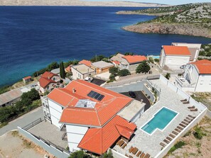 A coastal residential area with houses, a swimming pool, and a view of the sea.