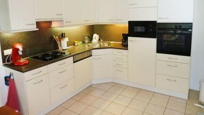 A compact kitchen with white cabinets, a black microwave, and a red kettle. - Vacation home 2+ by Interhome (Lochem)