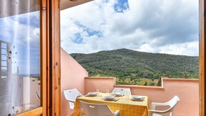 Un balc ón con una mesa dispuesta para dos personas, con vistas a un paisaje montañoso.