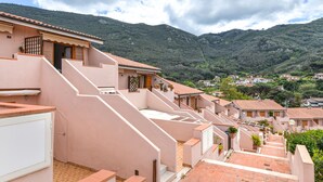 Un barrio residencial con casas adosadas, una escalera que lleva a una azotea y montañas al fondo.
