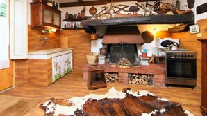Une cuisine rustique avec une cheminée en briques, des poutres en bois et un tapis en peau de vache.