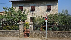 Un bâtiment en pierre à l’architecture traditionnelle, doté d’une entrée fermée par un portail et d’un panneau d’avertissement triangulaire.