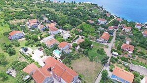 An aerial view of a coastal residential area with houses, some with red roofs, surrounded by greenery and a clear blue sea. - Moreška by Interhome (Orebić/Viganj)