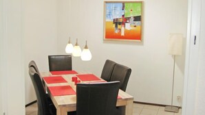 A dining area with a wooden table, black chairs, red placemats, and three pendant lights.