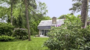 A modern house with a sloped roof, surrounded by lush greenery and trees.