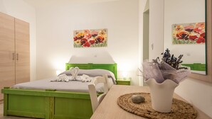 A bedroom with a green bed frame, a bedside table with a vase, and a painting of flowers on the wall. - Apartment Val by Interhome (Sveti Juraj)