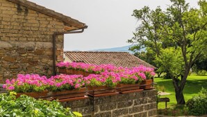 Un edificio de piedra con techo de tejas y jardineras llenas de flores rosas.