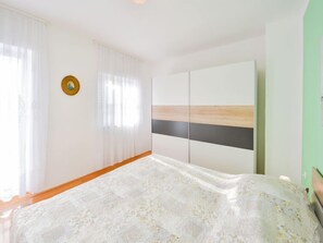 Une chambre à coucher avec un lit, une armoire et une fenêtre avec des rideaux.