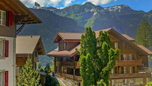 A mountain village with traditional wooden houses, a clear sky, and a mountain in the background. - Alpina Apt. CH by Interhome (Wengen)