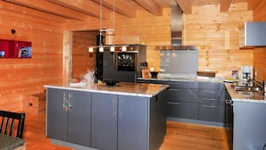 A modern kitchen with wooden walls, grey cabinets, and stainless steel appliances. - Alpina Apt. CH by Interhome (Wengen)