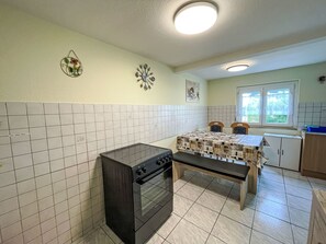 Una cucina con forno, bancone, pareti piastrellate e una finestra.