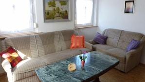 A living room with a sofa, a coffee table, and a painting on the wall. - Apartment Bless by Interhome (Schutterzell)