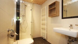 A modern bathroom with a glass-enclosed shower, a toilet, a sink, and a wooden cabinet above the mirror. - Apartment Werner by Interhome (Pettneu am Arlberg)