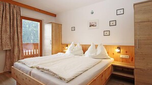 A bedroom with a wooden bed, a wardrobe, a window with curtains, and wall-mounted lights. - Apartment Werner by Interhome (Pettneu am Arlberg)