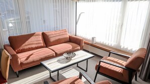 Un salon moderne avec un canapé, deux fauteuils et une table basse.