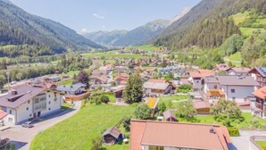 A mountainous village with traditional houses, a main road, and lush green hills. - Christian by Interhome (Pettneu am Arlberg)
