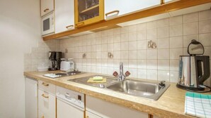 A kitchen with white cabinets, a double sink, a coffee maker, a toaster, and a kettle. - Christian by Interhome (Pettneu am Arlberg)