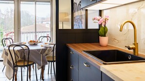 Una cocina moderna con armarios oscuros, encimera de madera y un lavamanos con grifo dorado.