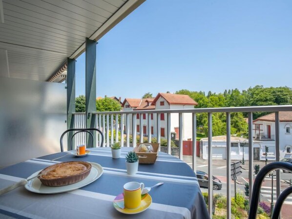 Ein Balkon mit einem Tisch für zwei Personen, einer Torte, einer Tasse und einer kleinen Pflanze.