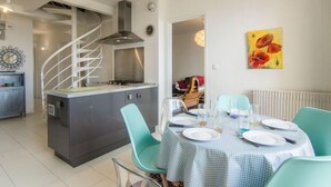 Une cuisine moderne dotée d’un îlot central, d’un escalier en colimaçon et d’un coin repas avec une table dressée pour quatre personnes.