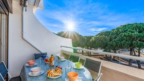 Ein Balkon mit Frühstückstisch, mit Blick auf eine von Bäumen gesäumte Gegend.