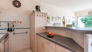 Eine Küche mit einer Kaffeemaschine, einer Obstschale und einer Weinflasche auf der Arbeitsplatte.