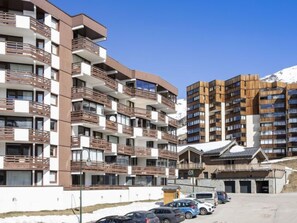 A multi-story hotel with balconies and a parking area.