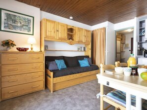A cozy room with a wooden sofa, a small table with a lamp, and a wooden cabinet.