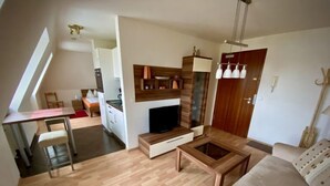 Een modern appartement met een eethoek, kitchenette, woonkamer en een televisie.