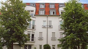 Een meerlaags woongebouw met balkons, ramen en een rode pannendak.