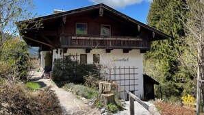 A traditional wooden chalet with a sloped roof, a balcony, and a stone pathway leading to the entrance.