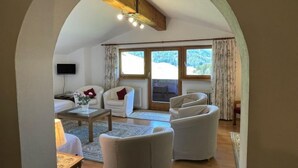 A cozy living room with a fireplace, comfortable seating, and large windows offering a view of the outdoors. - Kaiserhof by Interhome (Alpbach)