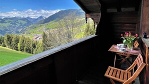 A wooden balcony with a table and chairs, overlooking a mountainous landscape. - Kaiserhof by Interhome (Alpbach)