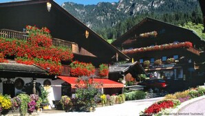 A traditional Alpine wooden building with balconies adorned with flowers, a visible shop, and a mountainous backdrop. - Kaiserhof by Interhome (Alpbach)