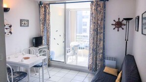 Een knus woongedeelte met een balkon, een eethoek en een bank.