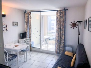 Ein kompakter Wohnraum mit Balkon, Essbereich und einer Couch.