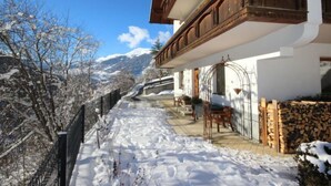 A snow-covered pathway leading to a building with a balcony and wooden railings.