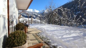 A snow-covered pathway leading to a building with a mountain backdrop.