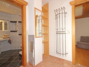 Une salle de bain moderne avec une douche, des toilettes et un lavabo. On y trouve un cadre de porte en bois et un miroir au mur.