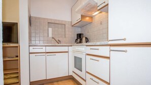 A kitchen with white cabinets, a stove, and a coffee maker.