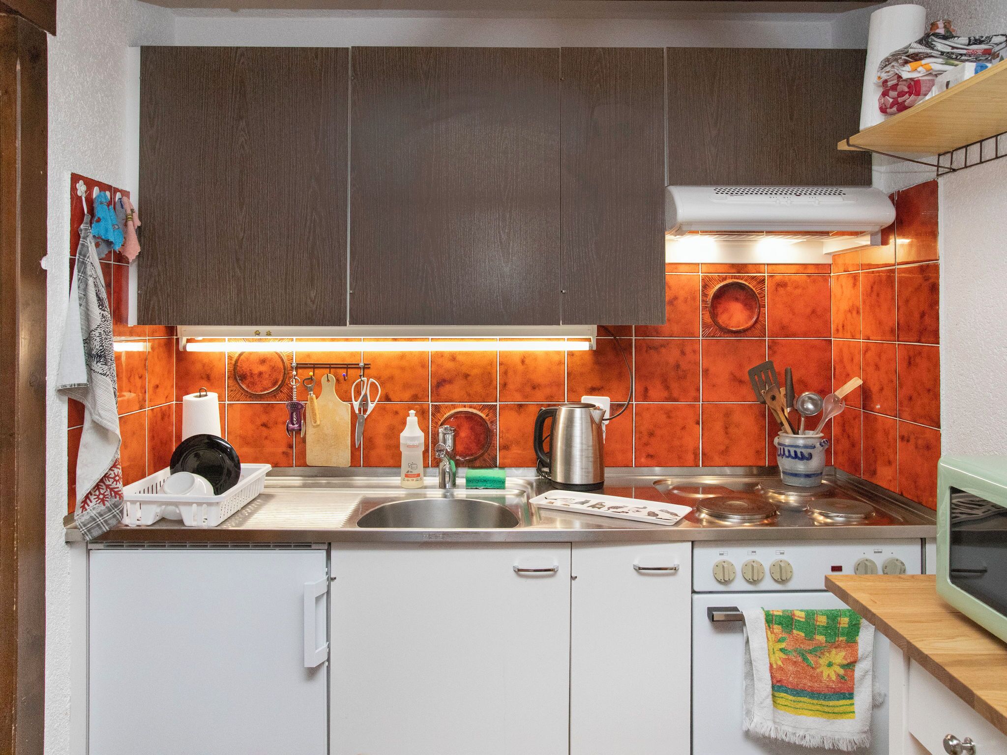 A kitchen with brown cabinets, a stainless steel sink, and a stove.