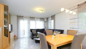 Ein modernes Wohnzimmer mit Esstisch, Sofa und Fernseher.