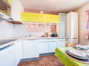 Une cuisine compacte avec des meubles blancs, une partie supérieure jaune et un four encastré.