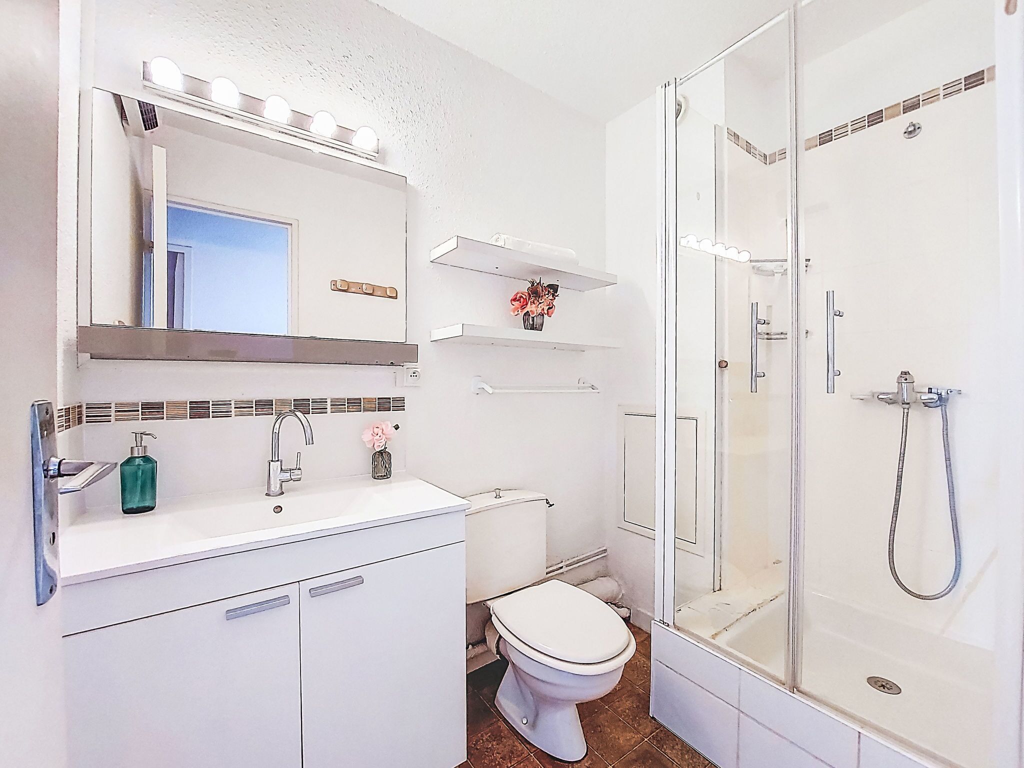 A modern bathroom with a white sink, vanity, and a glass-enclosed shower.
